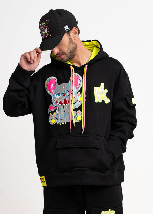 Person wearing a black hoodie with colorful graphics and black pants on a white background