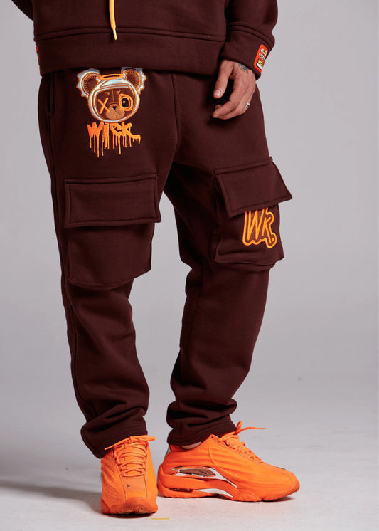 Brown tracksuit with orange accents worn by a person on a gray background