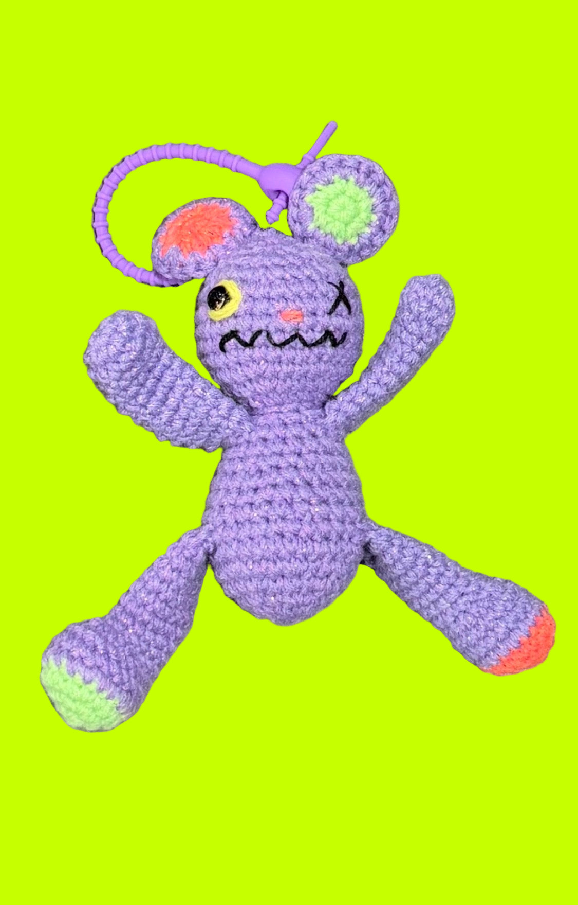 Purple crochet toy with a sad face on a gray concrete surface