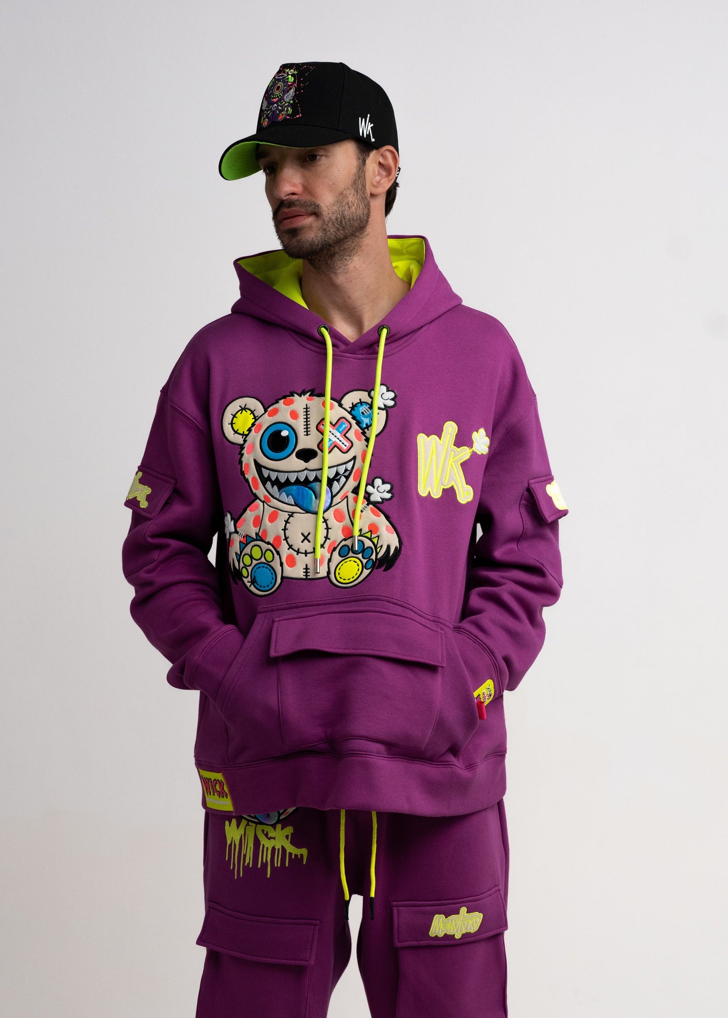 Person wearing a purple hoodie and pants with colorful graphics on a white background