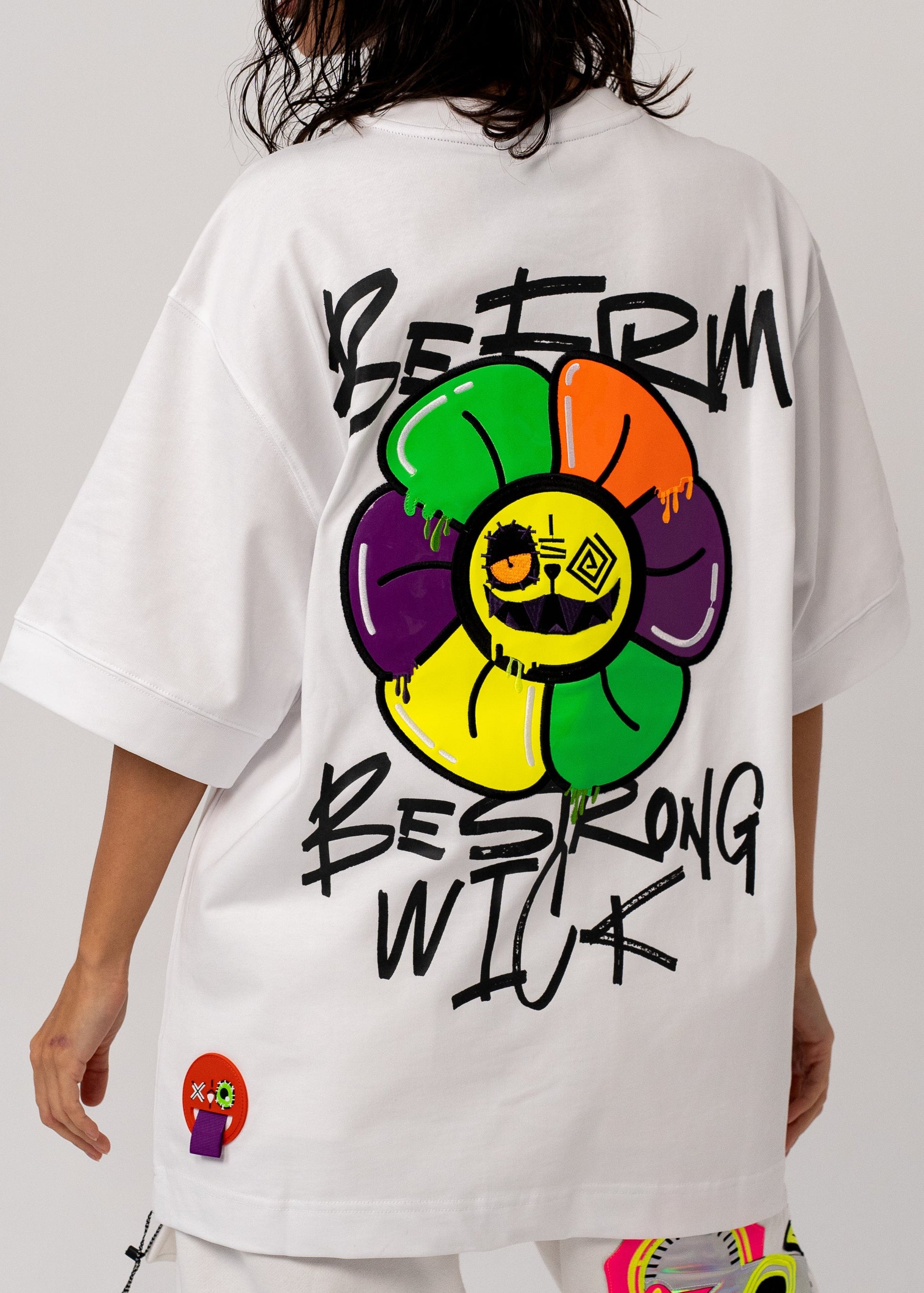 Person wearing a white outfit with colorful designs and text on a plain background