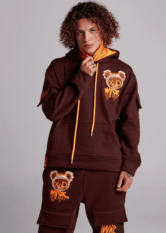 Person wearing a brown hoodie and pants with bear graphics and 'MK' logo on a gray background