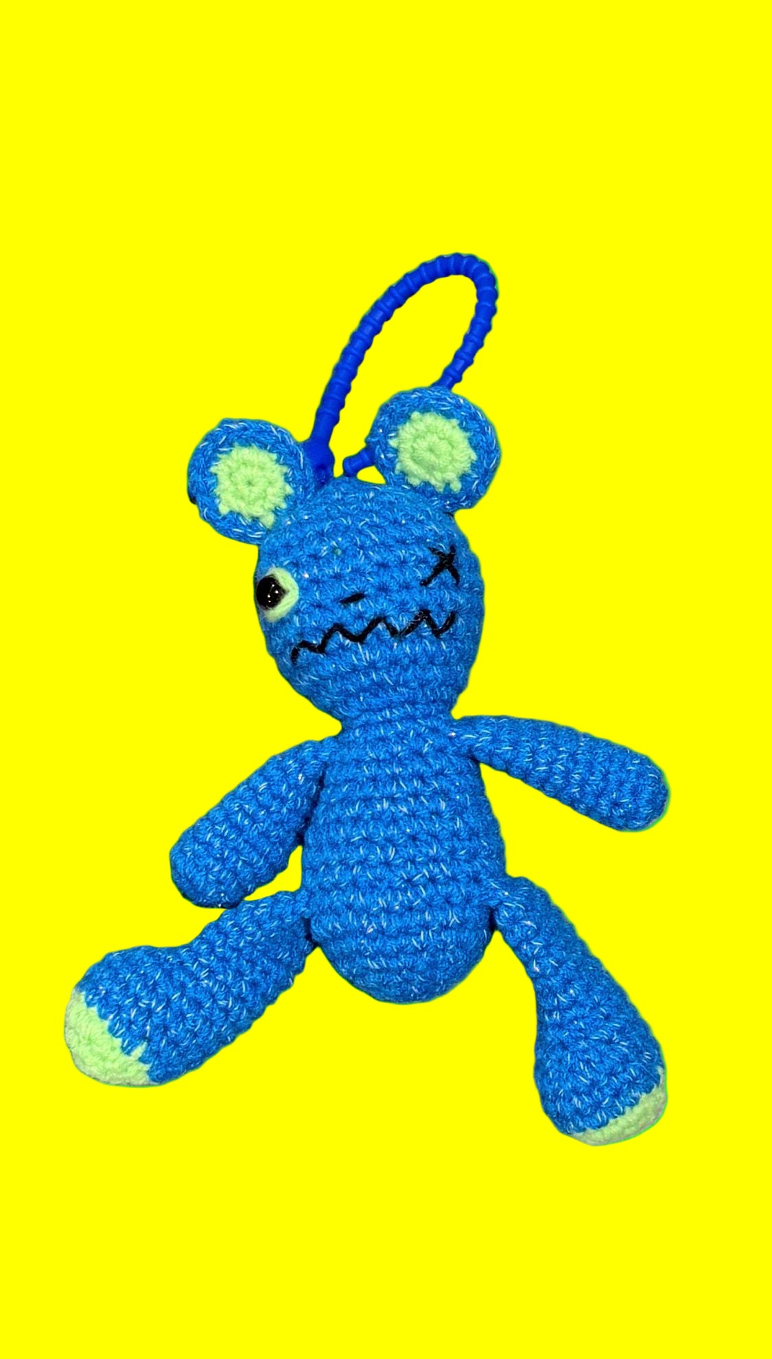 Blue plush toy with a sad expression on a green background