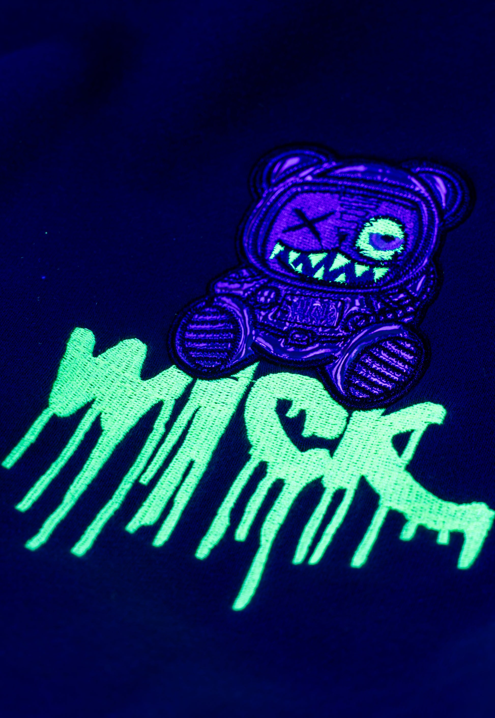 Glowing purple and green patch with a bear-like creature design on a dark background