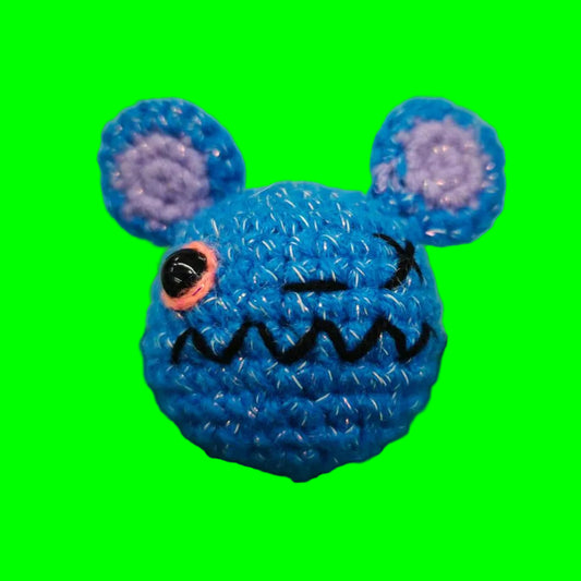 Blue crocheted mouse toy on a green cutting mat